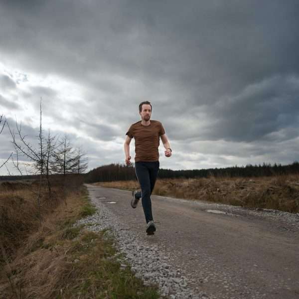 Man running under clouds on gravel road